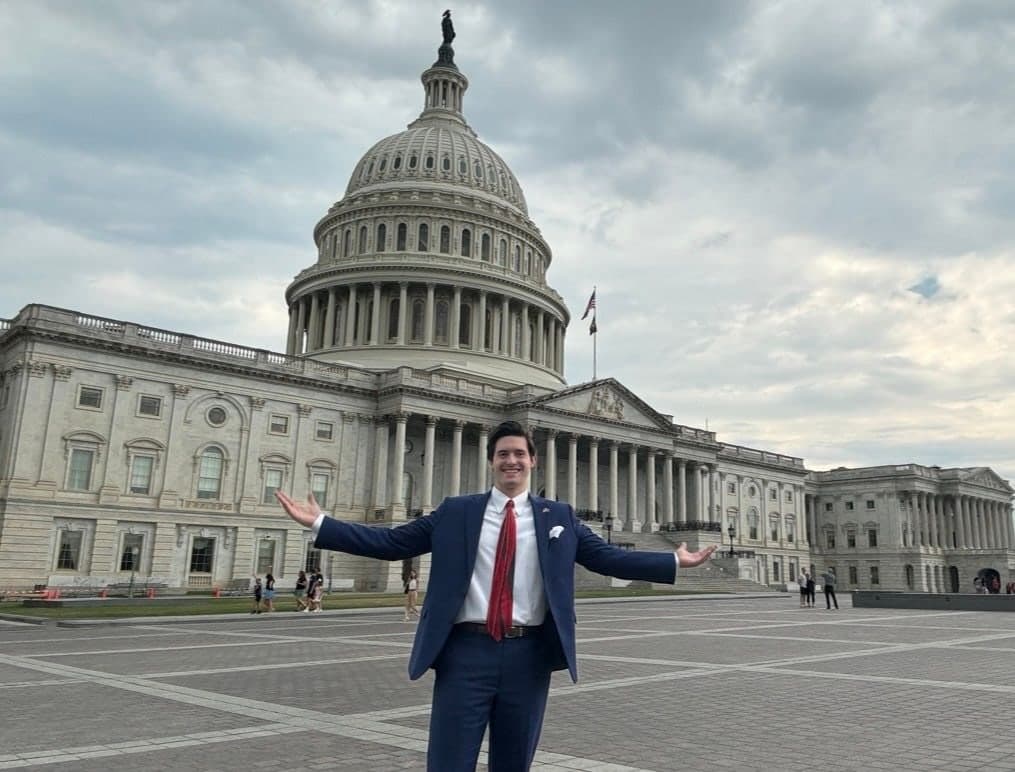 Colin Raby with arms outstretched in front of the U.S. Capitol dome