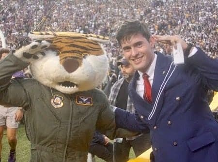 Colin Raby saluting beside Mike the Tiger in a flight suit in Tiger Stadium