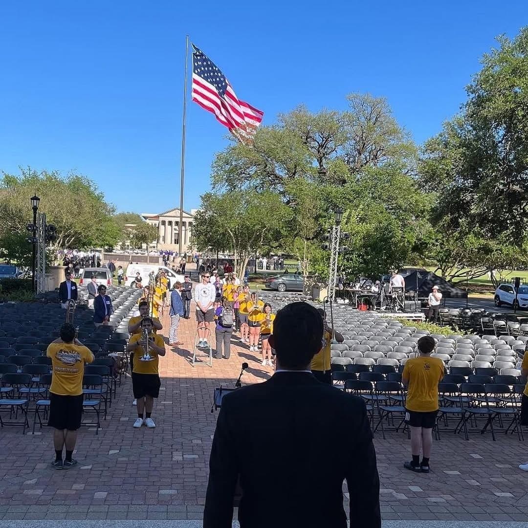 Colin Raby looking out over the Memorial Tower rededication ceremony at LSU, an American flag flying above the crowd