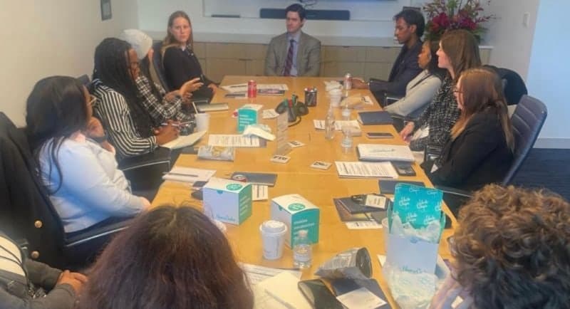 Colin Raby seated at the head of a conference table leading a discussion with FIU scholars