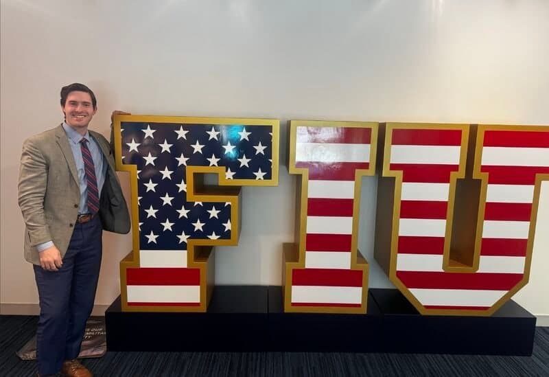 Colin Raby beside a large FIU sign decorated with stars and stripes