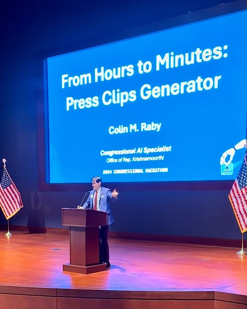 Colin Raby at the podium in the Capitol Visitor Center Auditorium beneath his title slide, “From Hours to Minutes: Press Clips Generator”