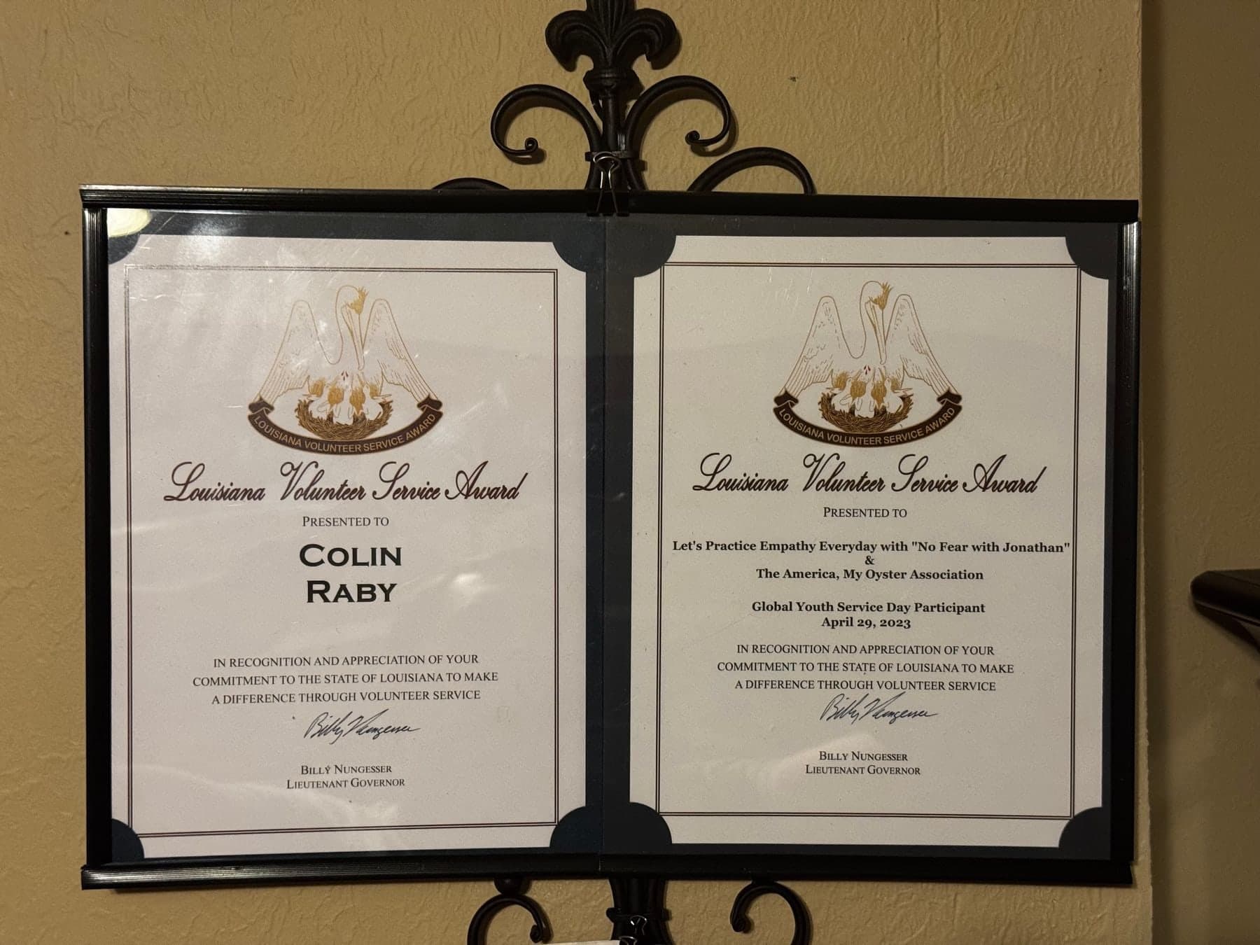 Two framed Louisiana Volunteer Service Award certificates signed by Lt. Gov. Billy Nungesser: one presented to Colin Raby, the other to the Global Youth Service Day project he took part in on April 29, 2023