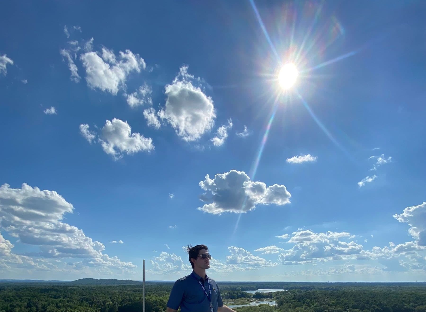 Colin Raby standing atop a NASA rocket test stand above the treeline