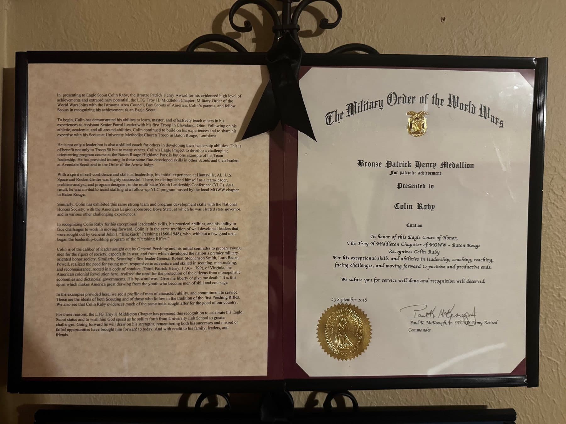 The framed Bronze Patrick Henry Medallion certificate from the Military Order of the World Wars, presented to Colin Raby on Sept. 23, 2018, beside the chapter's letter of citation