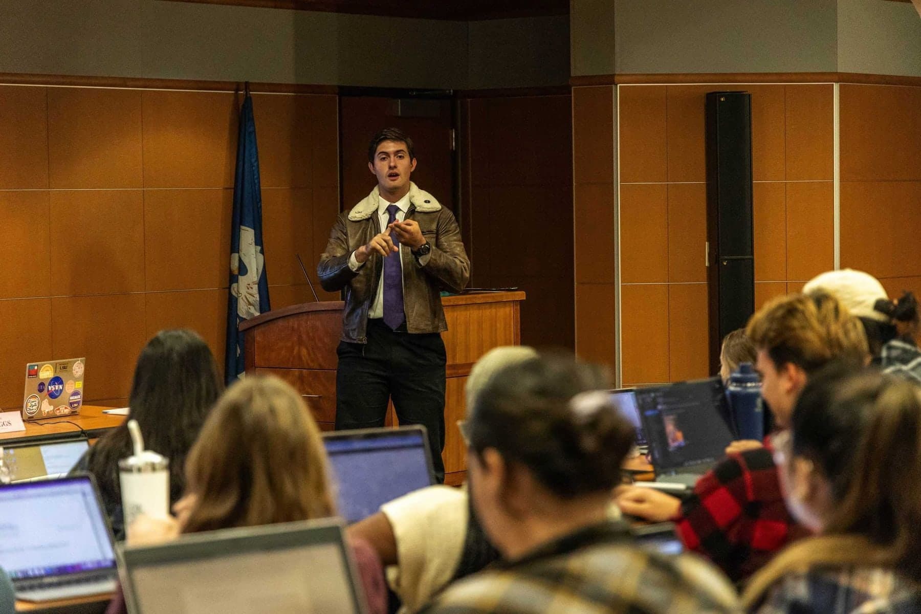Colin Raby standing at the front of the LSU Student Government chamber addressing senators seated at laptops