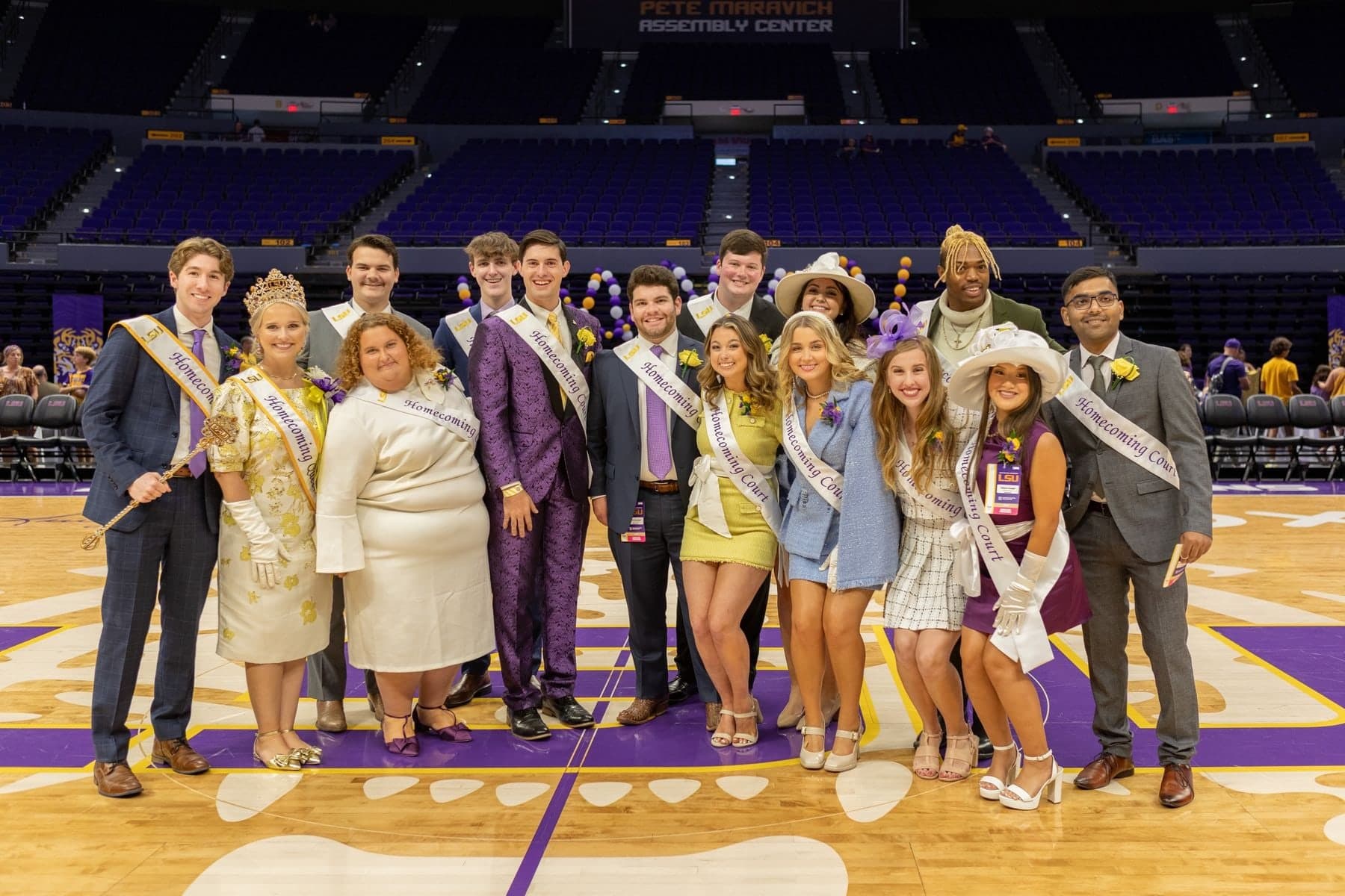 The fourteen members of the 2023 LSU Homecoming Court posing together on a basketball court